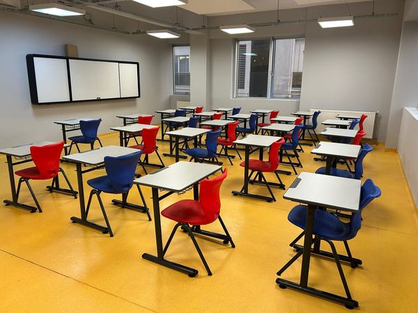 Kırmızı ve mavi sandalyeli, beyaz tahtalı aydınlık derslik