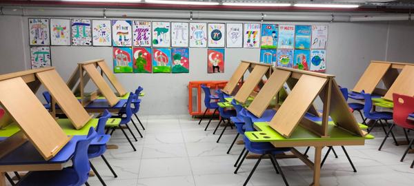 Şövaleli çalışma masaları ve öğrenci resimleriyle resim atölyesi