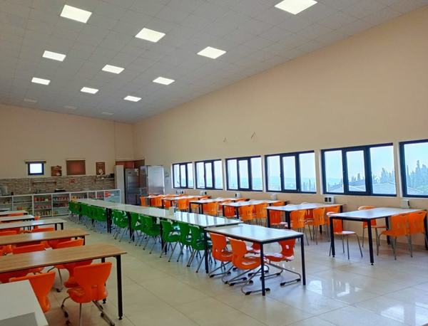 Geniş pencereli, aydınlık yemekhane ve renkli sandalyeler