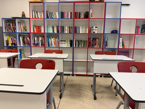 Renkli raflı sınıf kitaplığı ve öğrenci sıraları