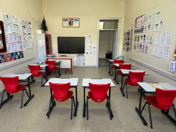 Kırmızı sandalyeli, duvarları İngilizce kelime kartlarıyla donatılmış sınıf