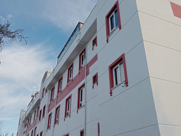Kırmızı pencere çerçeveli beyaz okul binasının yan cephesi