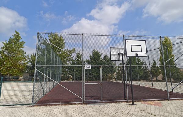 Tel çitle çevrili kauçuk zeminli açık basketbol sahası