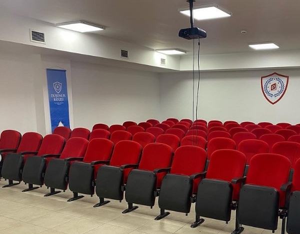 Kırmızı koltuklu ve projeksiyon cihazlı konferans salonu