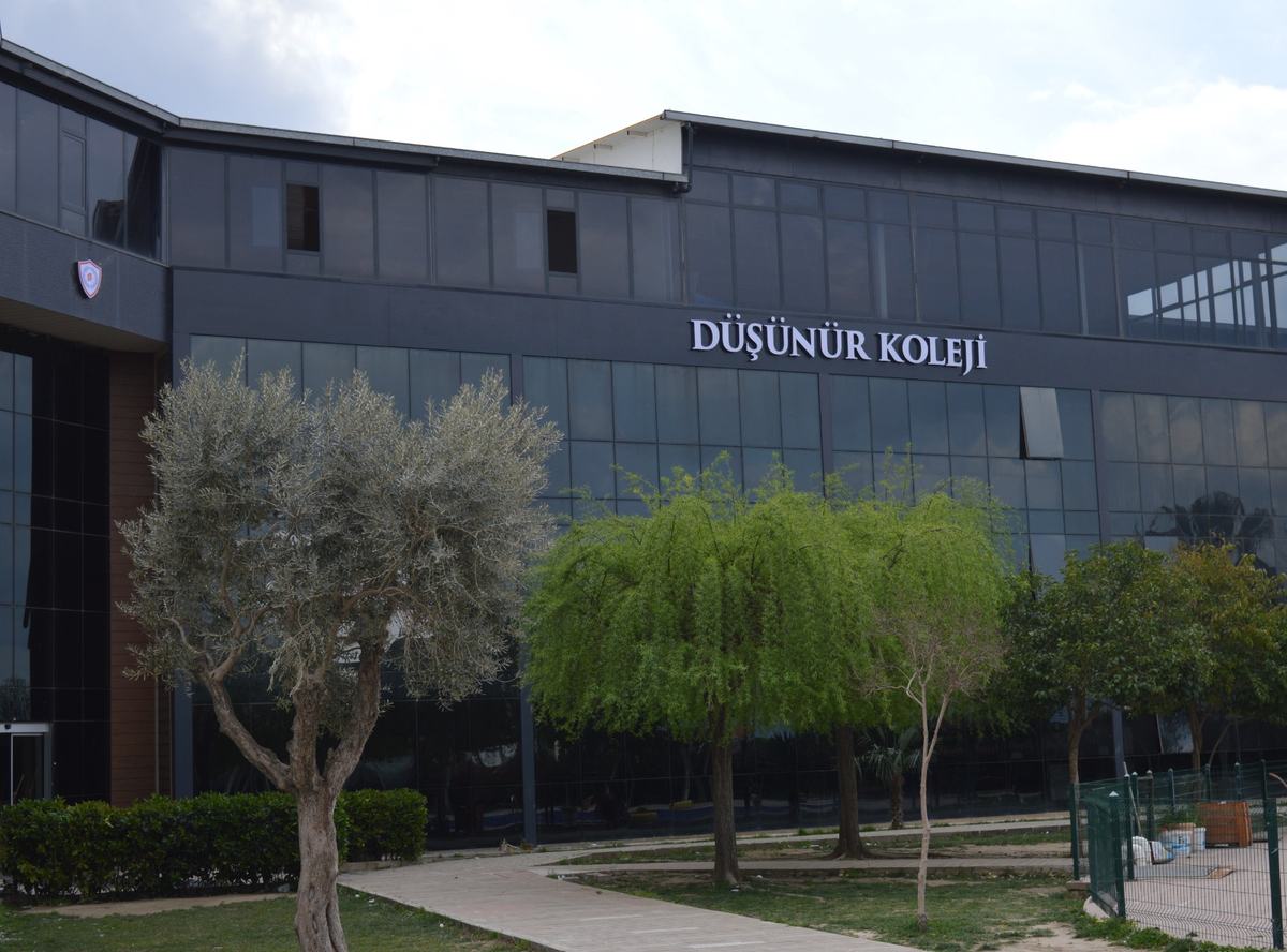 Manisa Kampüsü ana binası, okul tabelası ve bahçe ağaçları