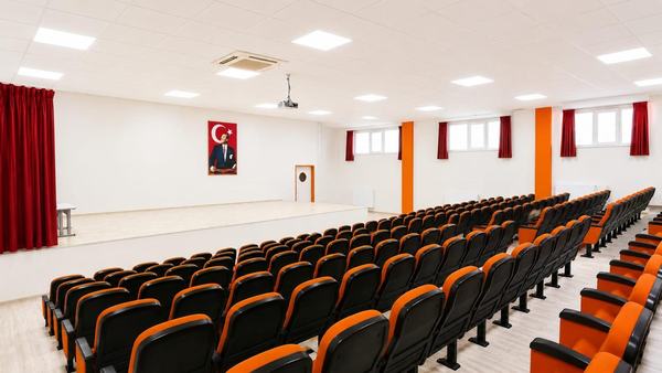 Sahneli ve turuncu koltuk sıralı konferans salonu