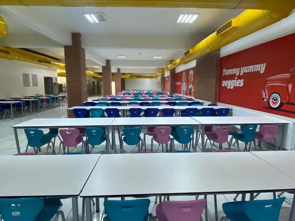 Renkli sandalyeli, tuğla sütunlu geniş yemekhane