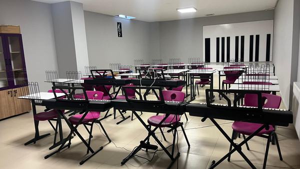 Elektronik klavyeler ve nota sehpalarıyla donatılmış müzik sınıfı