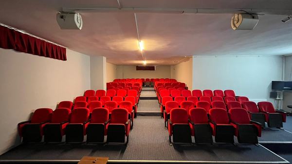 Kırmızı koltuklu, kademeli oturma düzenine sahip konferans salonu