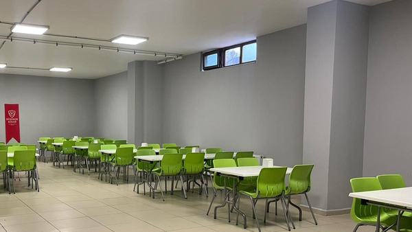 Okul flamasının asılı olduğu yeşil sandalyeli geniş yemekhane